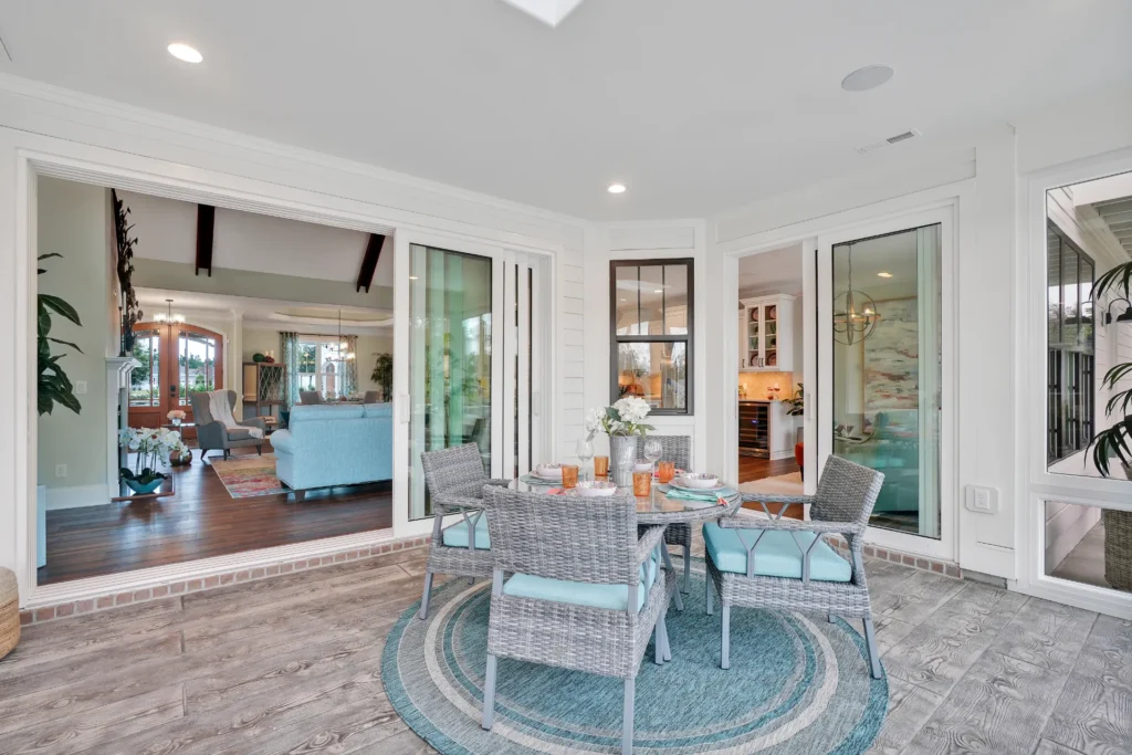 Bright indoor-outdoor living room with wicker patio furniture, light blue accents, and natural wood tones.