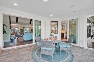 Bright indoor-outdoor living room with wicker patio furniture, light blue accents, and natural wood tones.