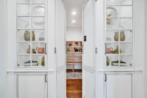 Bright pantry with glass cabinets, wooden shelves, and organized decorative storage in a modern home.