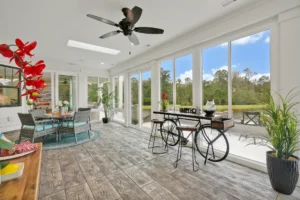 Bright modern sunroom with glass walls, rustic wood floors, and cozy indoor-outdoor seating.
