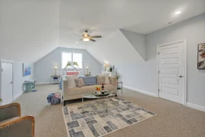 Bright modern attic living room with beige sofa, soft gray walls, and natural light.