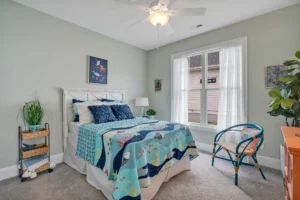 Coastal bedroom with blue ocean decor, wicker accents, and natural light for a relaxing vibe.