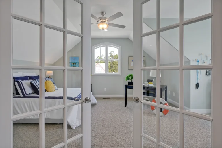 Cozy attic bedroom with French doors, soft gray walls, and natural light.
