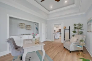 Bright neutral home office with white desk, beige armchair, and natural light for a serene workspace.