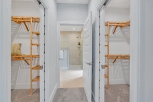 Modern master suite hallway with dual walk-in closets leading to a bright contemporary bathroom.